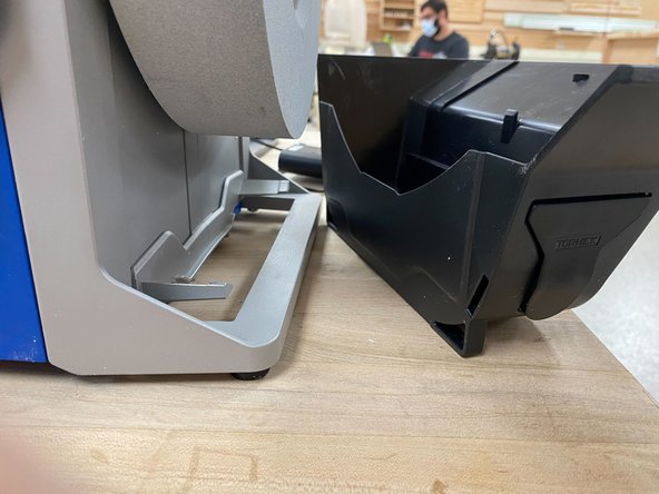 To remove the grindstone, the water trough must first be removed by using the knob on the back of the grinder to lower the trough. Then pull the trough out of the way to allow the grindstone to come free.