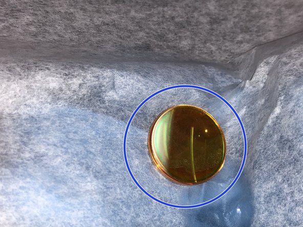 Use some Acetone and lens paper to gently clean the lens in circular motion.