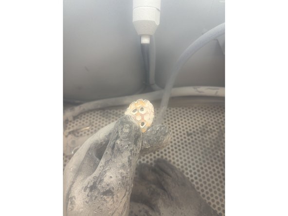 Its finally time to Sand blast that thang. Insert your hands into the gloves. Pick up the part within the chamber and position it a few inches away from the static nozzle. Use the pedal under the desk to sandblast away. For heavily covered parts utilize the sand gun at long distance to blast at full pressure.