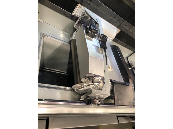 Locate the metal roller underneath the left side of the fusing carriage