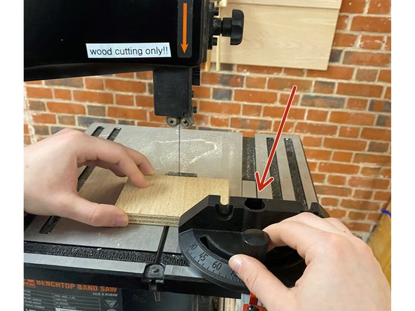 Push the material through the band saw smoothly and slowly to achieve a clean cut.