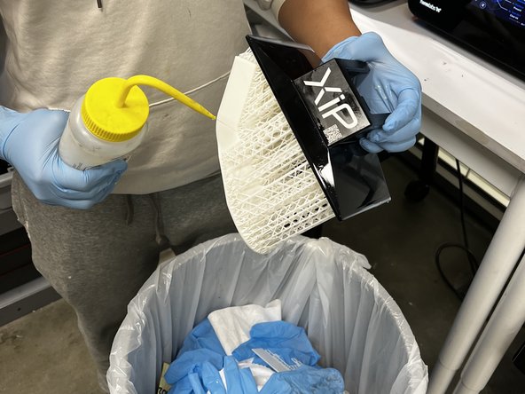 Rinse the part with IPA over a trash can to remove  liquid resin.