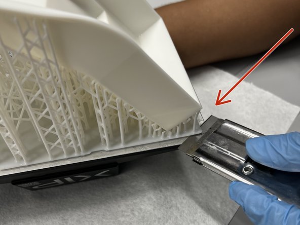 Use a razor blade to carefully separate a corner of the model raft from the build plate.
