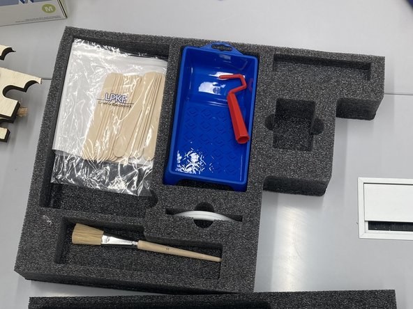 One part contains a roller, a paintbrush, handles for holding the board, and popsicle sticks