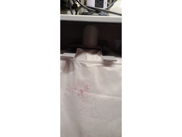 First, push down on the metal holder. It will swing downwards and detach the bag from the input tube. (Pictures 1 and 2)