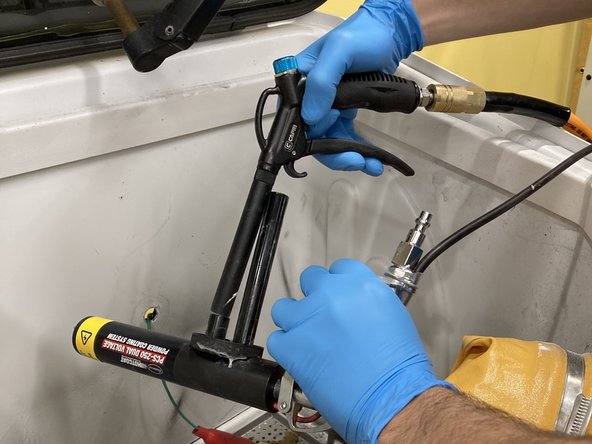 Working inside of the powder coating tub with the vacuum on, unscrew the current bottle from the powder gun