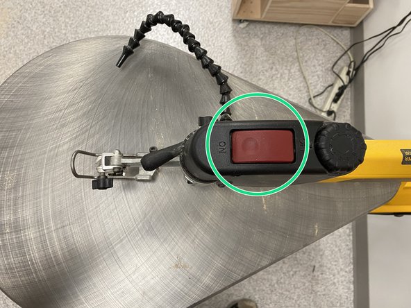 Flip the red power switch on the top of the scroll saw.