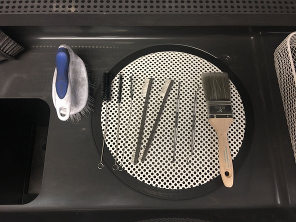 Use brushes, picks, and other tools to clean the powder off of the prints