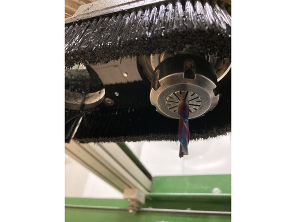 Using the two wrenches in the top drawer of the desk, loosen the collar of the spindle to access the collet and tool. Once desired tool and collet are in place, screw the collar back onto the spindle and tighten firmly