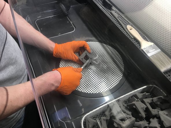 Try lightly tapping the part on the grate to knock powder out of hard to reach areas