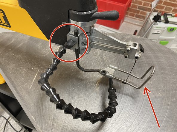 Move the workpiece guard to the desired height by adjusting the black knob on the left side of the scroll saw.