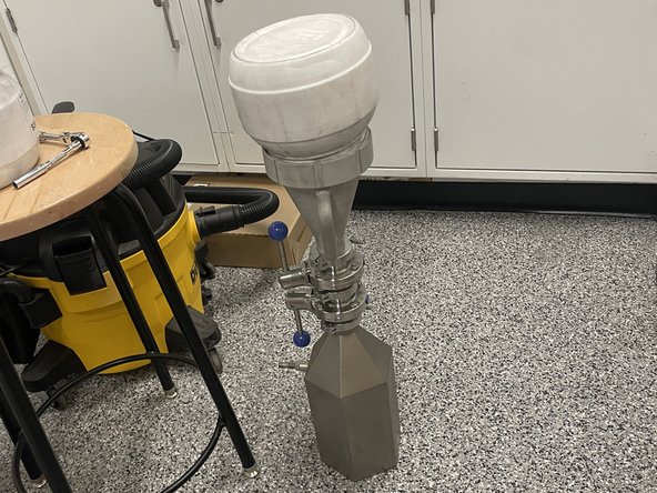 Firstly you will take the bottle off of the top of the machine by locking both ends of the piping system so that powder cannot flow (both handles should be vertical). Then loosen the O-ring collar. The supply bottle may still be heavy so carefully take it off the top of the machine.