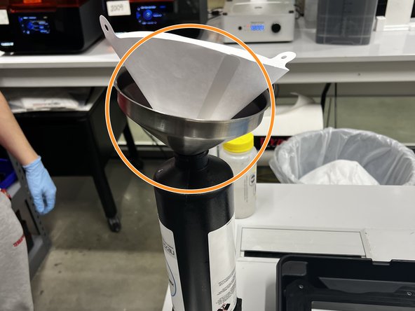Set up a paper filter and funnel on top of the open cartridge as shown in the picture. The filter and funnel can be found in the Nexa storage area.