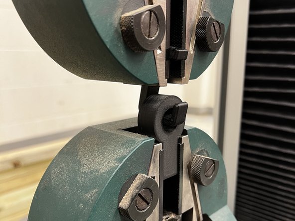 Turn the large silver knobs to clamp the test hook and base in the jaws. You may need to use the jog slider again to move the jaws during this process.