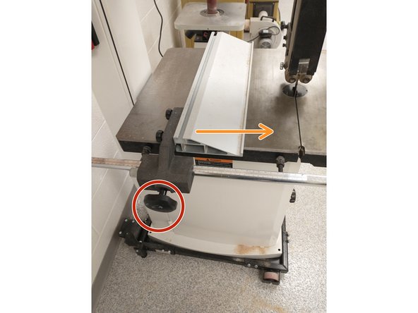 Turn the knob at the front of the bandsaw to loosen the fence. It can then be moved to the desired position.