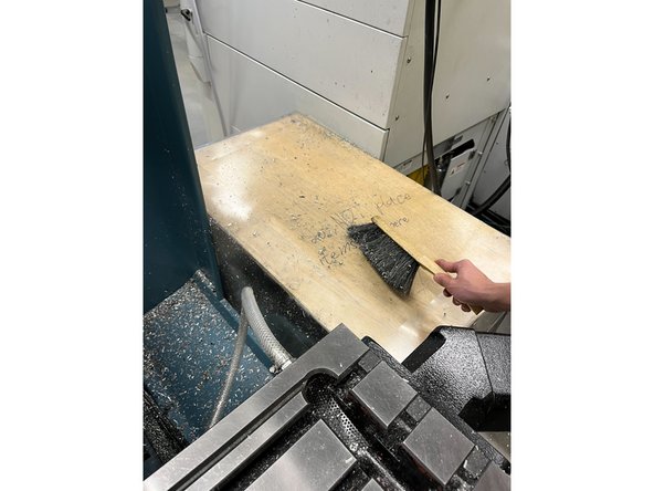 Use the brush to clean any fallen chips off the table at the side and into the pan