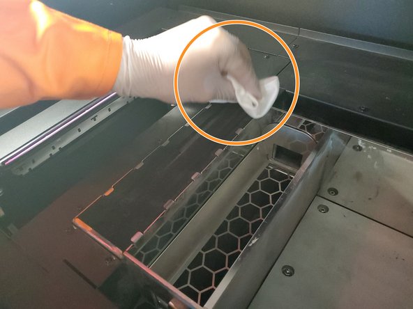 With a lint-free cloth and DI water, clean the spit pad (on the left) gently