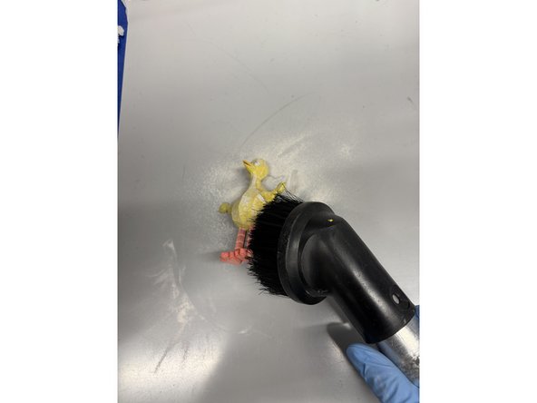 Turn the vacuum on and begin removing any excess dust on the part. Then turn your attention to the workspace and vacuum any accumulated sand.