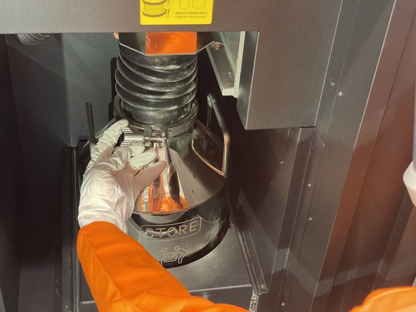 Carefully disconnect the powder chute by undoing the clamp