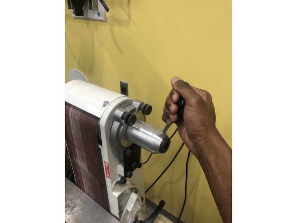 Release the belt tension using the handle, and slide the belt off the wheels in one motion.