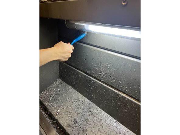 Continue to use the steel wire brush to brush the chips off the back of the wall into the tray underneath