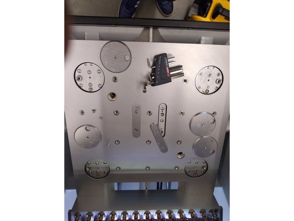 Remove the caps as shown  in the picture and grease the holes, then replace the caps and the vacuum table.