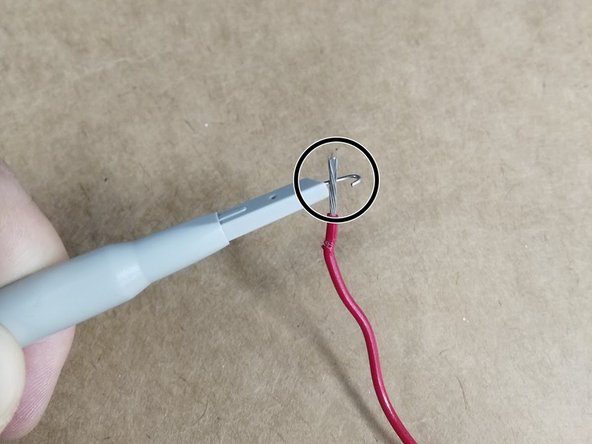 Pull back the plastic cover of the probe to reveal a metal hook. Hook this around what you want to measure.