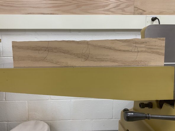 Begin pushing board across cutting head. Apply pressure both down into outfeed table AND into the fence to ensure a perfect 90° cut.