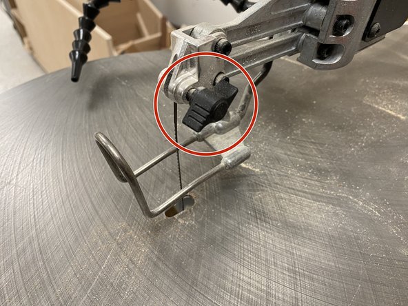 First, untighten the two black knobs that are both above the saw table, and underneath the saw table.