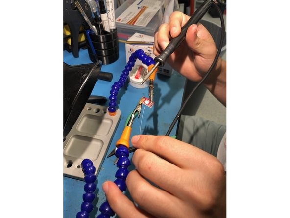 Now it is time to solder! Grab a soldering iron, preferably with your dominant hand, and the previously cut soldering wire