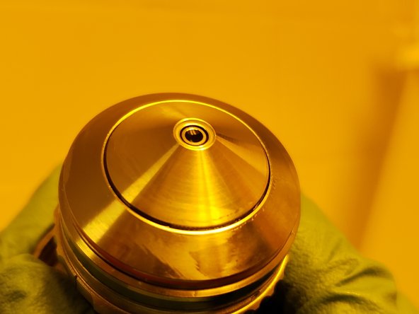 Hold the objective so that light is reflected off the lens and check for any streaking or residual resist.