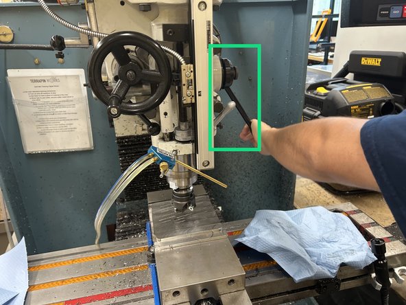 Using the wheel on the right to adjust the side-to-side position of the plate and the front wheel to adjust the forward-to-back position of the plate, position the plate directly under the face mill so that the center of the face mill is directly above the center of the build plate.