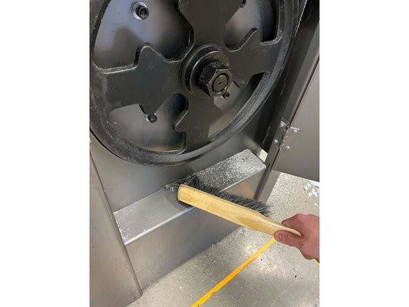 Open the door and using a brush, sweep the dust and shavings to the opening on the right. Be sure to dust off the wheel and door as well.