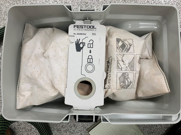 Undo the black latches on either side of the vacuum (only one is pictured).