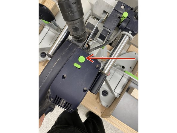 The Miter Saw has a green button for the laser guide on the back side of the handle facing the wall.