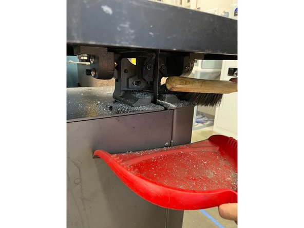 Use the brush and dustpan to clean below the table.