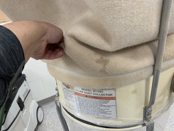 Lift the edges of the canvas bag to loosen and remove dust trapped between the bag and dust collector.