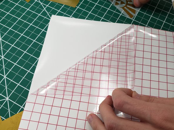 Lift up the transfer paper (the clear paper with red lines) from the base paper, and CAREFULLY apply it to the FRONT side of the vinyl sticker (the sheer side without the plastic backing)