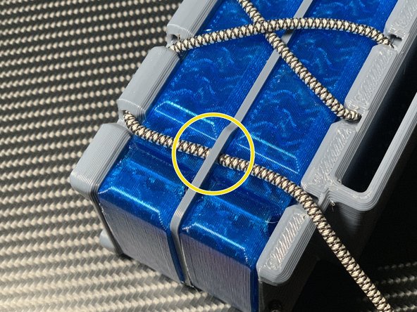 Then, pull diagonally to make an X, thread downwards, and pull through the lower hole. The X prevents the Warp Saya from flexing too much.