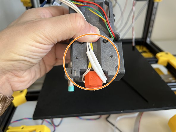 Hold the hotend thermistor and heater cartridge cables as seen in the picture.