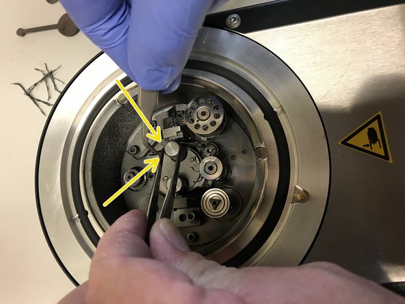 Hold a flat tweezer with one hand and a 2nd finer tweezer with the other. With the flat tweezers you lift the metal pin head and with the other tweezers you guide the carbon wire under the metal pin and clamp the wire by releasing the metal pin head by the flat tweezers.